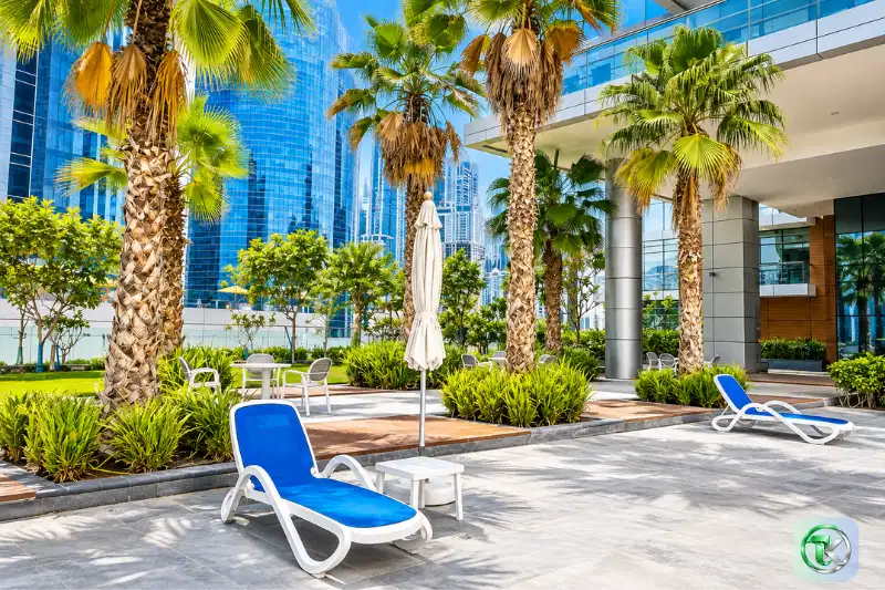 Outdoor terrace with palm trees and sun loungers at The 9 Tower, Dubai